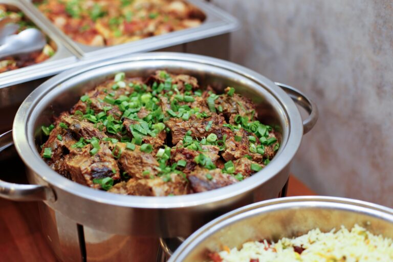 Mouth-watering buffet showcasing meat and rice with green onions in stainless steel dishes.